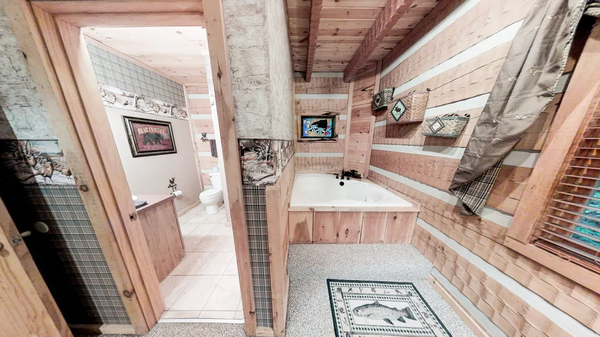 Showcasing a luxurious jacuzzi tub surrounded by wooden paneling, decorative wall art, and a textured rug, this bathroom scene exudes warmth and tranquility. The setting hints at self-care and relaxation after a day of adventure.